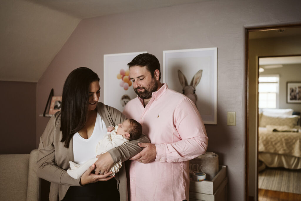 newborn lifestyle picture of family holding baby in the nursery