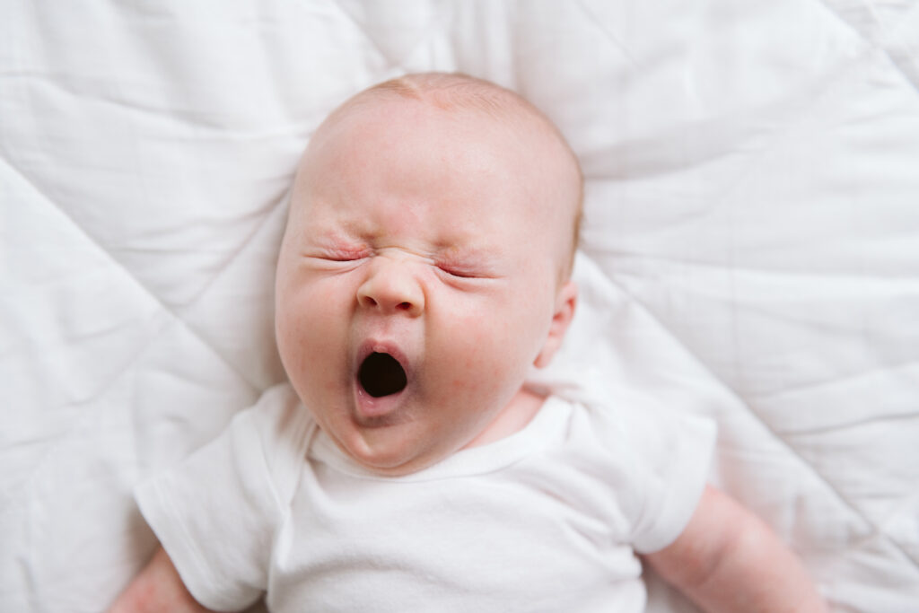 yawning newborn portrait in modern white studio