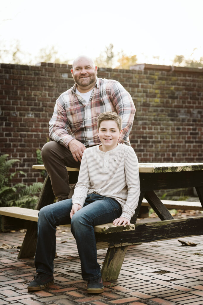 father and son sitting on a picnic table during a portrait session in Pittsburgh's Mellon Park