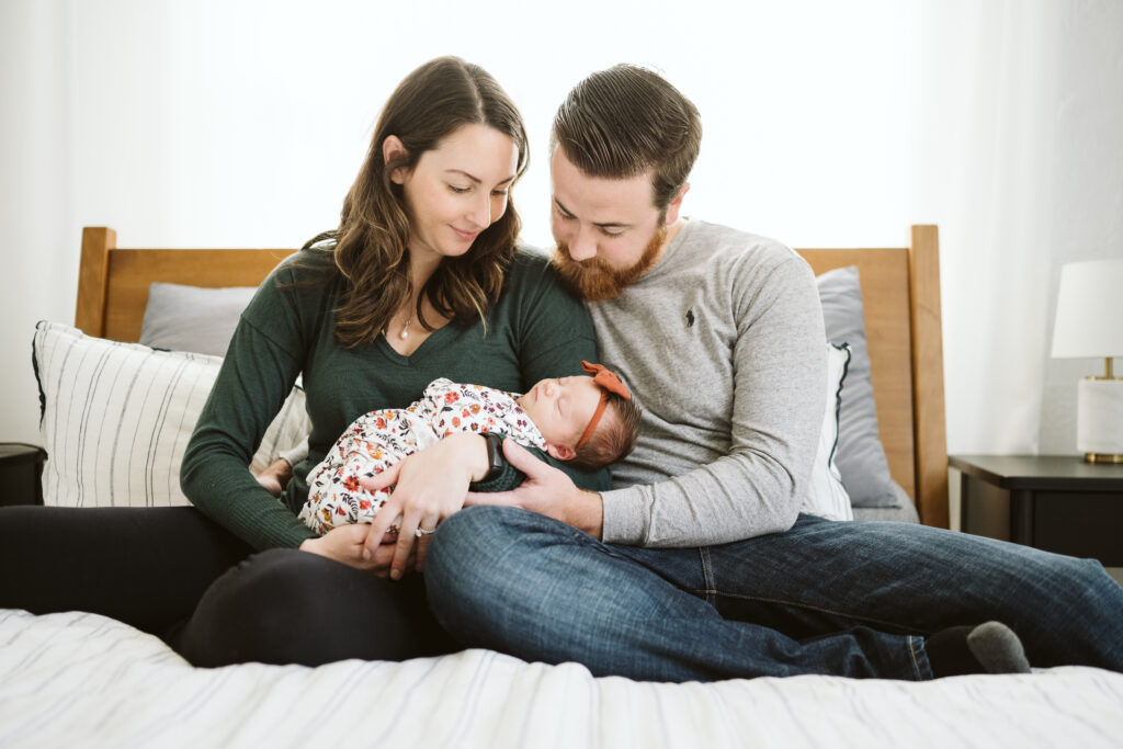 Pittsburgh family sitting in bedroom holding newborn baby