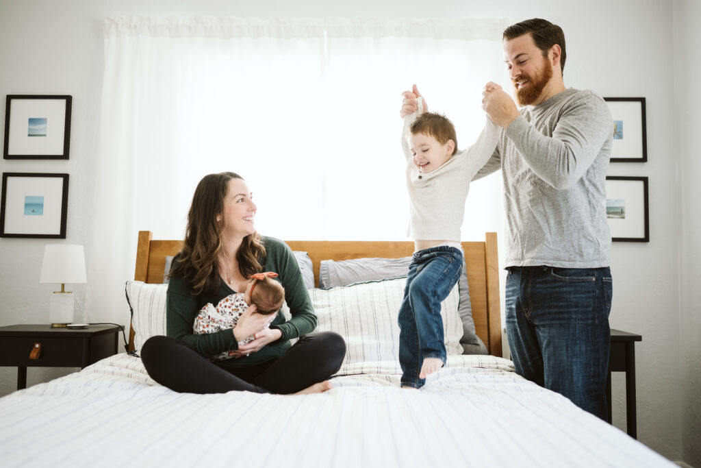 Pittsburgh family sitting in bedroom holding newborn baby