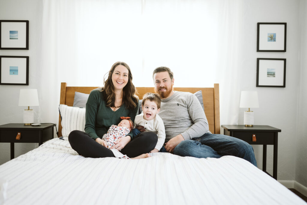 Pittsburgh family sitting in bedroom holding newborn baby