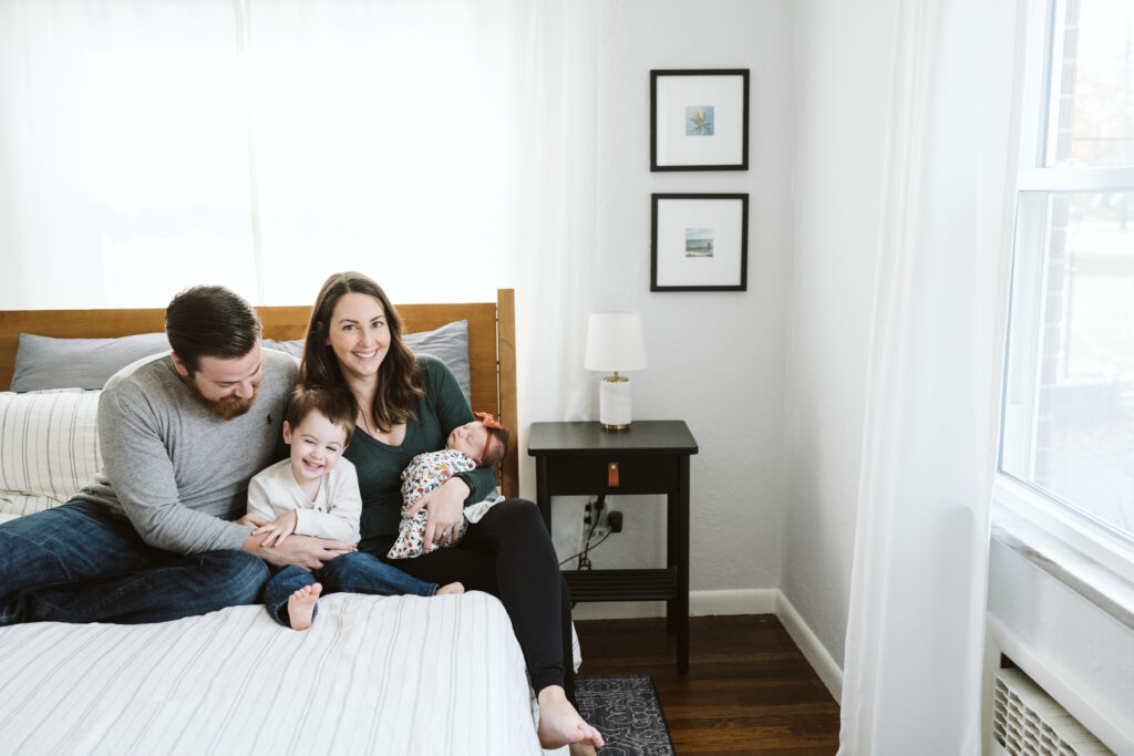 Pittsburgh family sitting in bedroom holding newborn baby