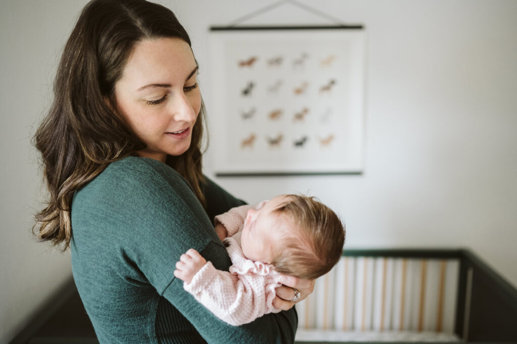 mom holding newborn baby in nursery