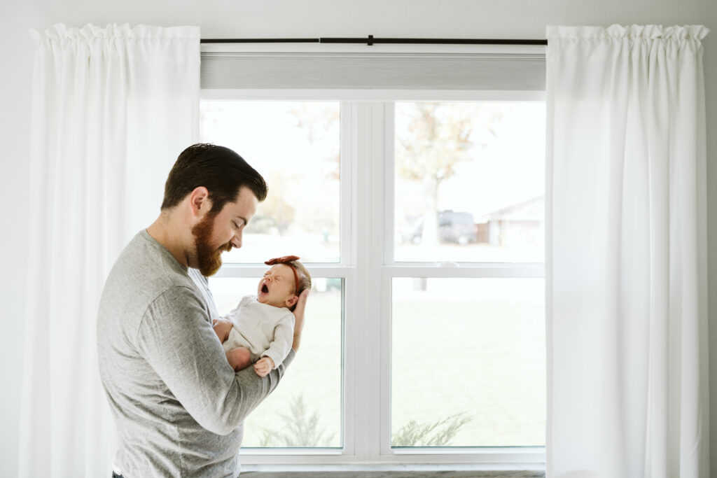 Pittsburgh dad holding newborn baby near window