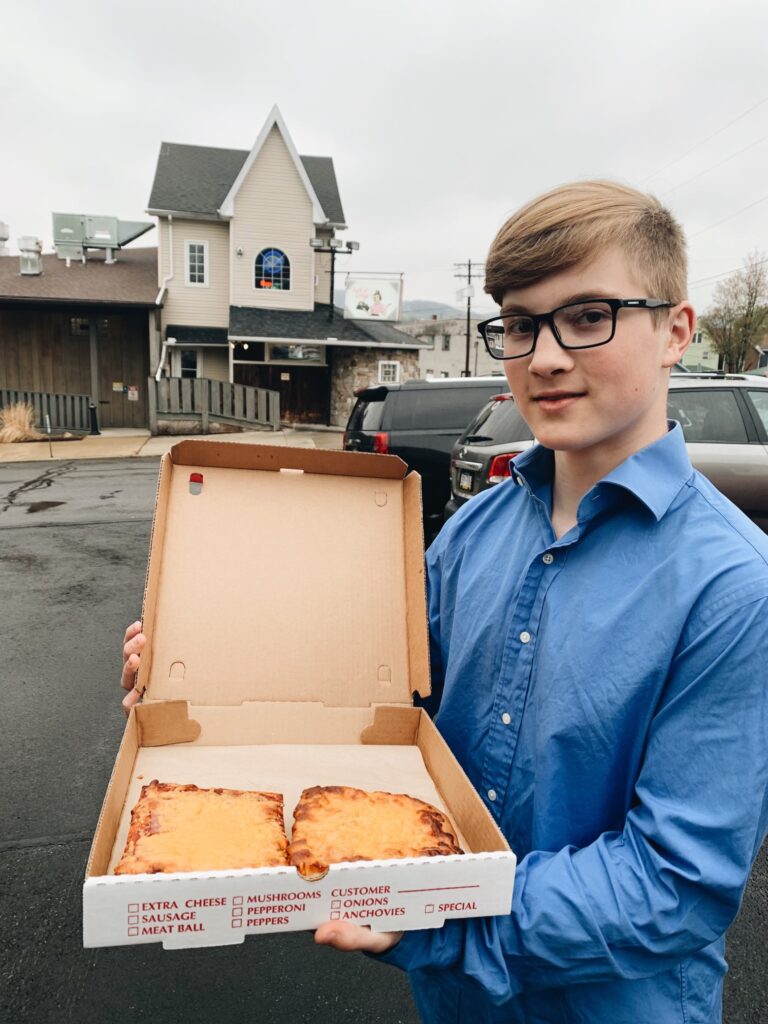 Ben Mares holding a box of altoona style pizza