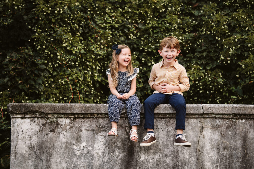 portrait of kids laughing while sitting on wall