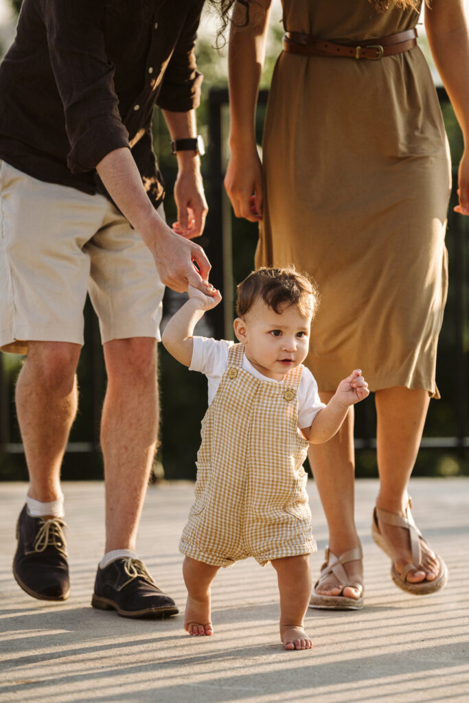 son holding dad's finger and walking during sunrise