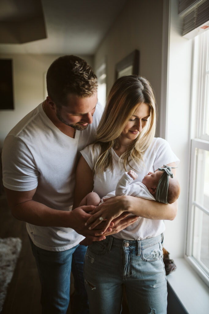 newborn lifestyle picture of family holding baby with dog at home