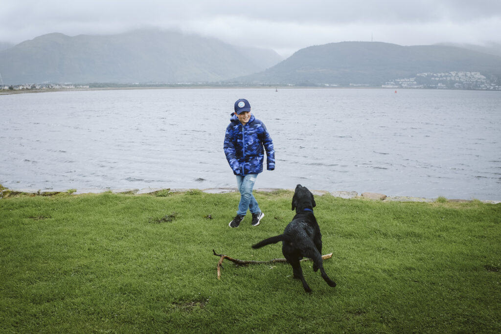 boy and dog playing fetch at Ben Nevis, Scotland