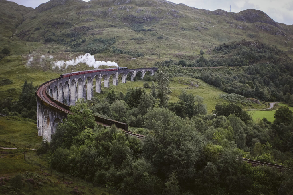 Steam train traveling across Glenfinnan Viaduct, Scotland
