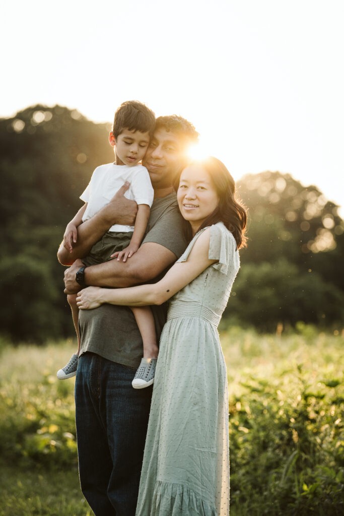 family posing for a portrait in a rural field with a sun flare near Pittsburgh, PA