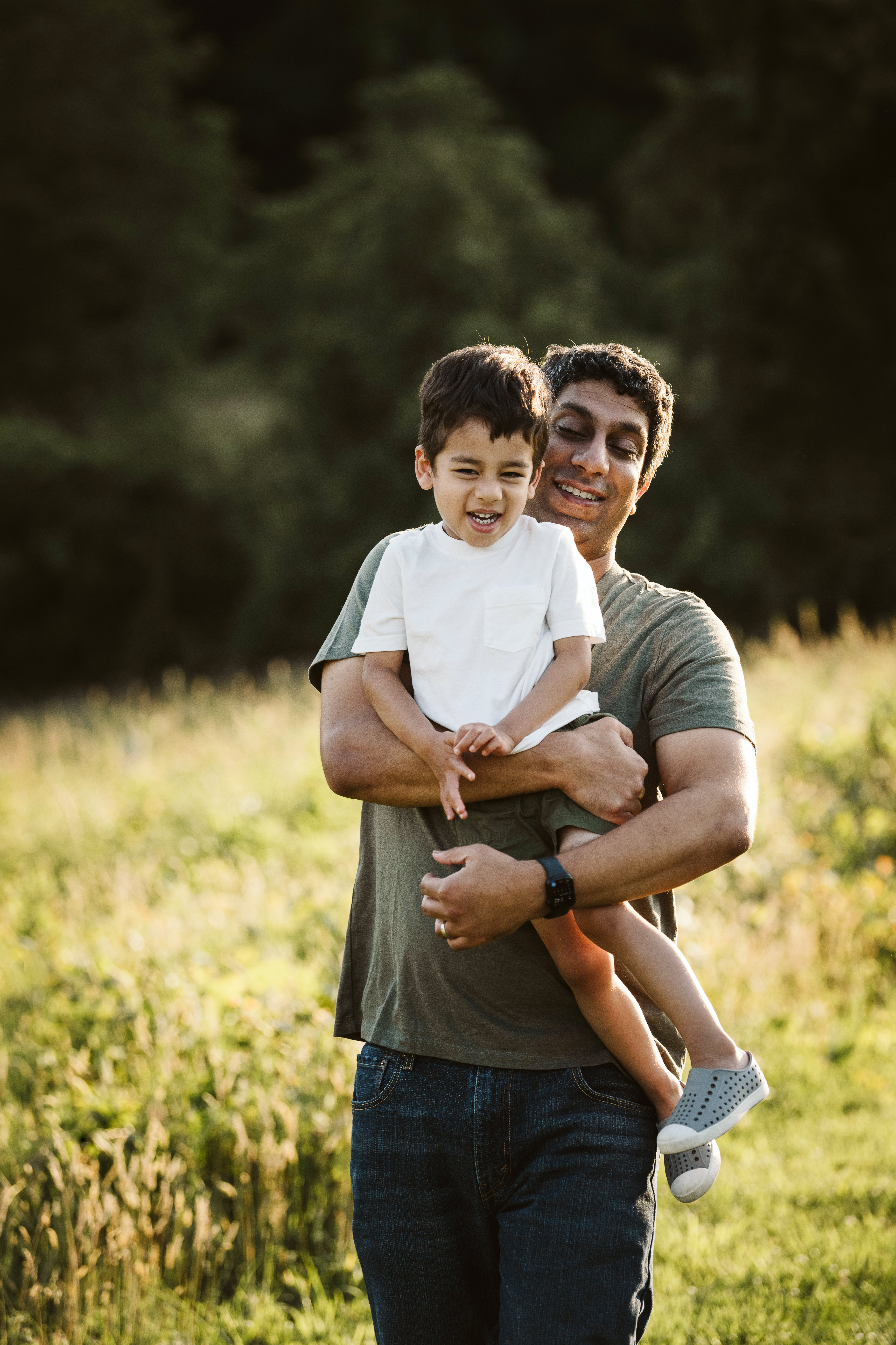 father and son posing for a portrait in a rural field with a sun flare near Pittsburgh, PA