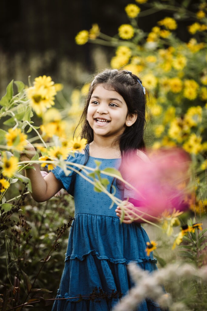 young child smiling in flower garden