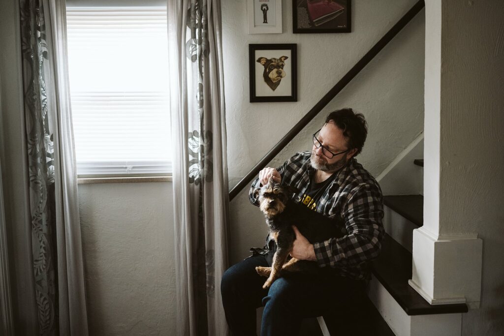 editorial portrait of man with dog sitting on steps
