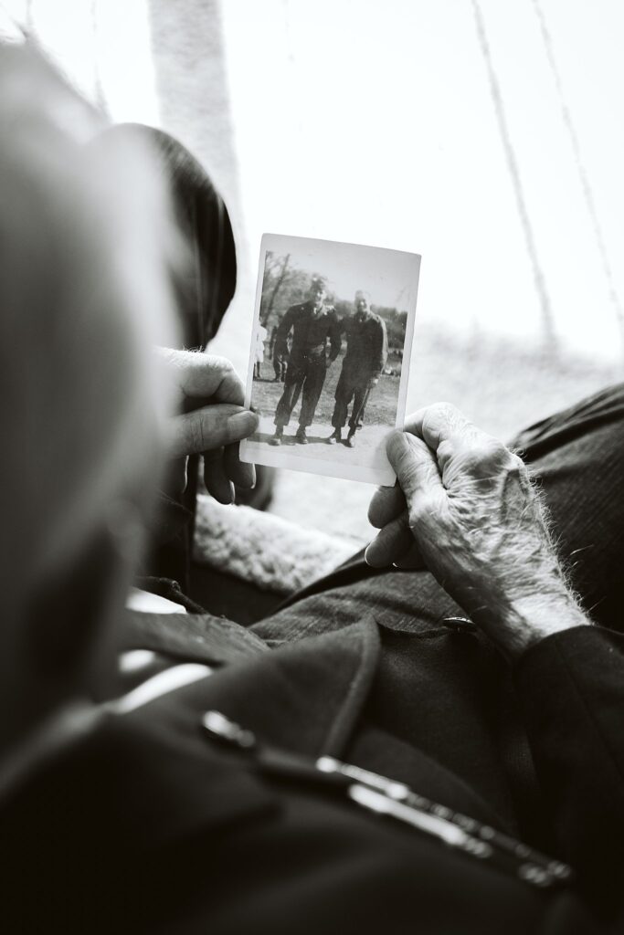 black and white editorial photograph of World War Two veteran holding a photograph from the 1940s