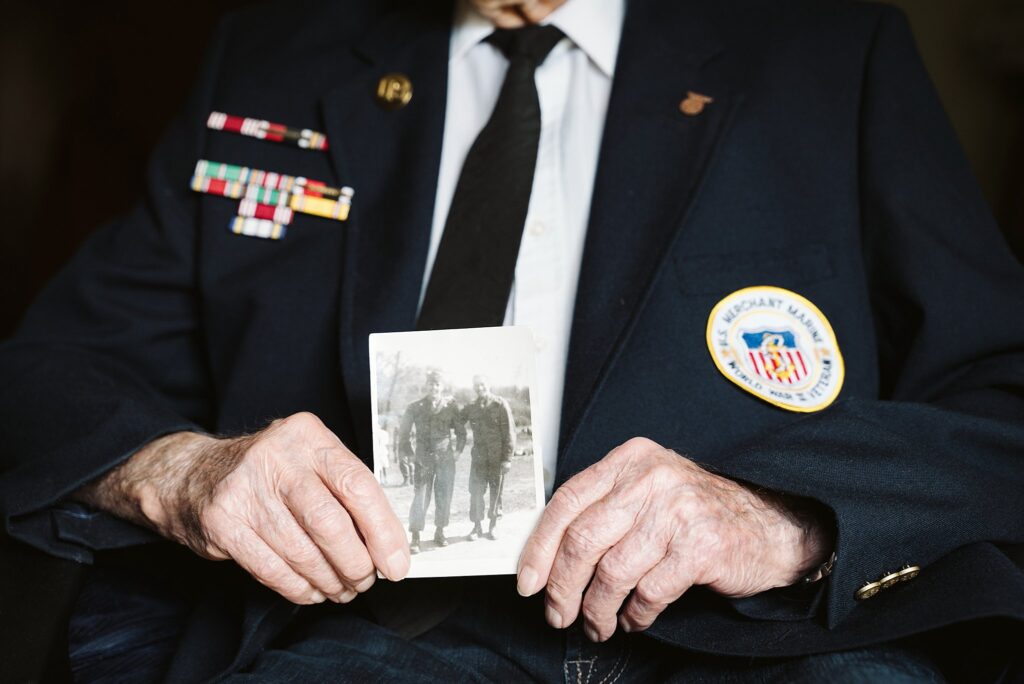 World War Two veteran holding a black and white photograph from the 1940s