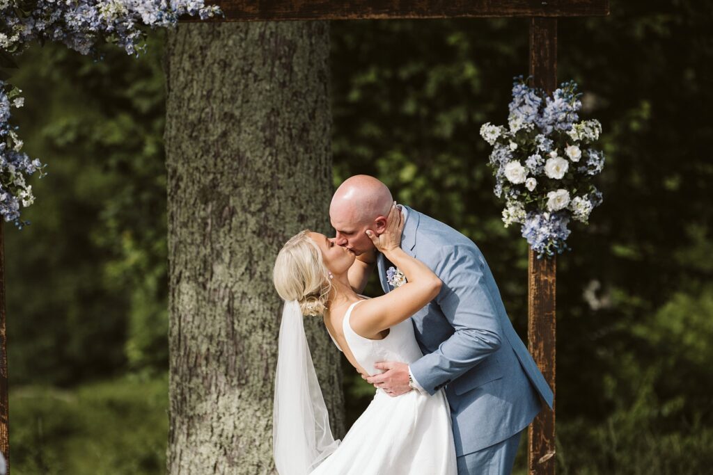 bride and groom kiss during outdoor wedding ceremony