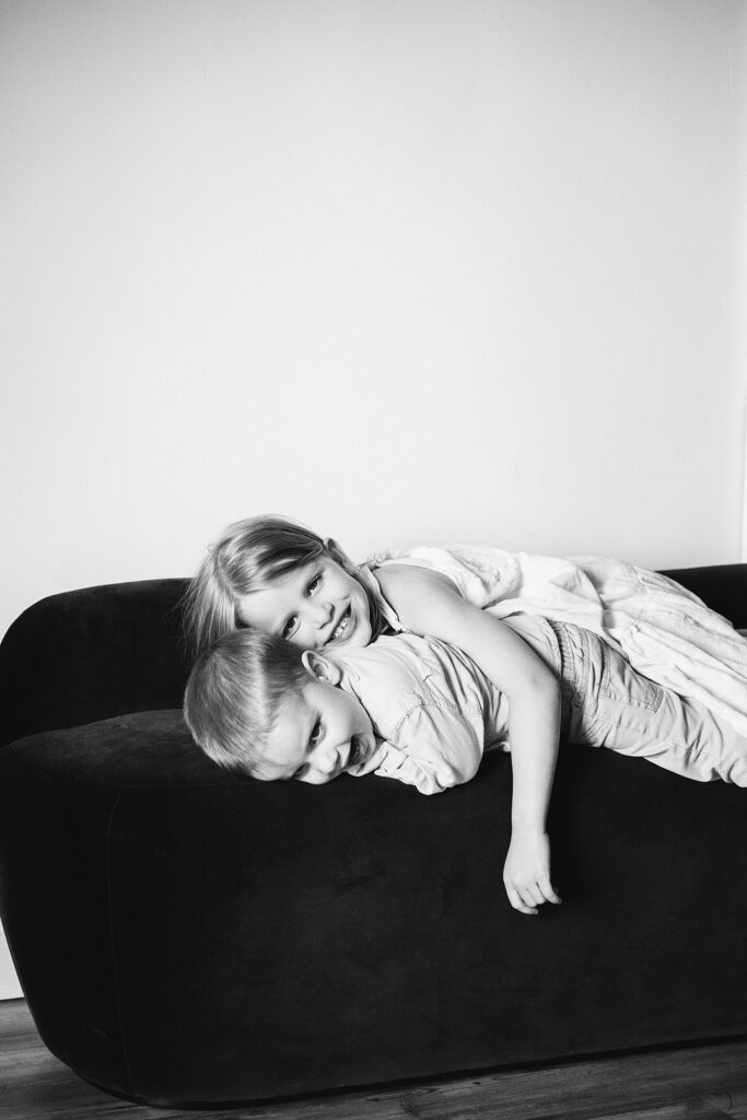 big siblings playing on bed during newborn photoshoot