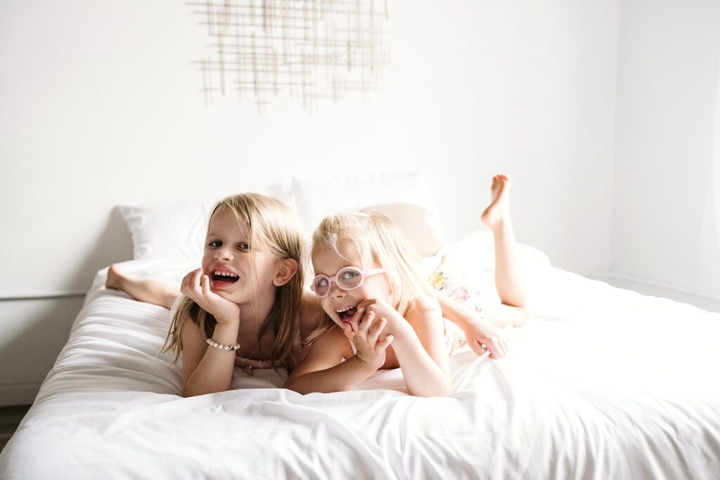 big siblings laughing on bed during newborn photoshoot