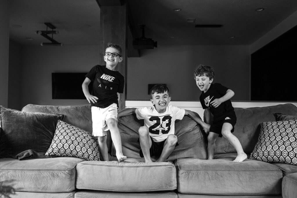 three boys jumping on a sofa during a lifestyle photoshoot at home in Pittsburgh