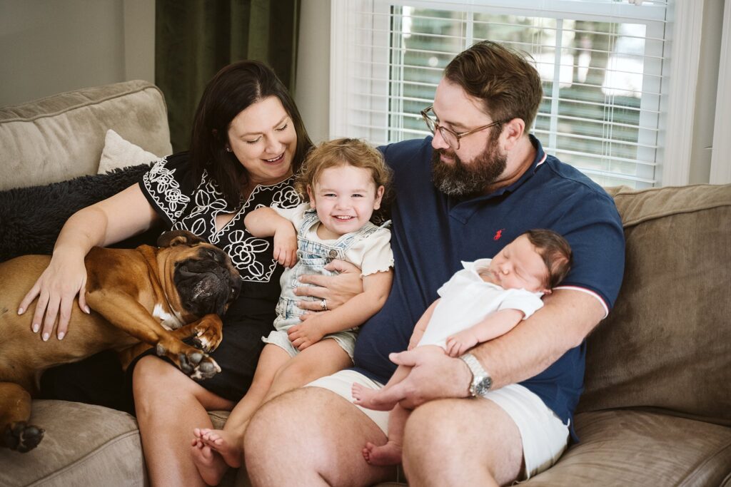 family sitting on a sofa during a newborn lifestyle photo shoot