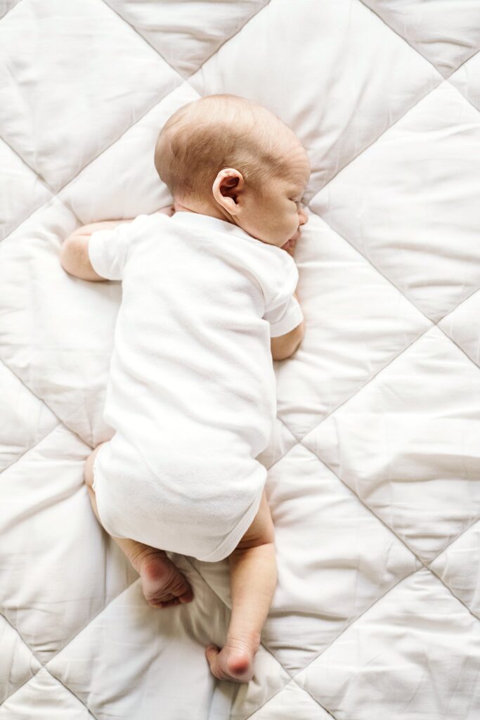 natural portrait of newborn baby laying on white bed in white studio