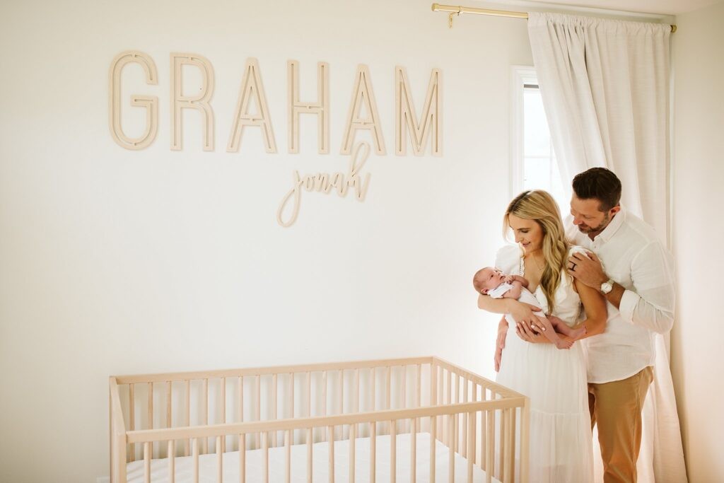 lifestyle portrait of a newborn with mom and dad in nursery