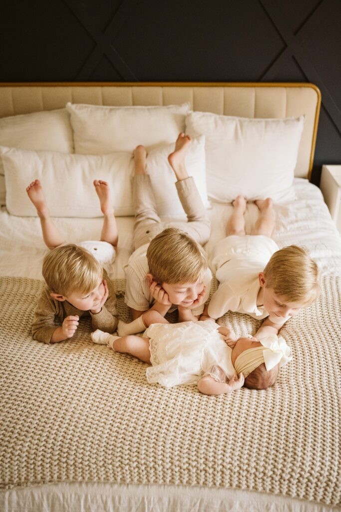 lifestyle portrait of siblings laying on bed