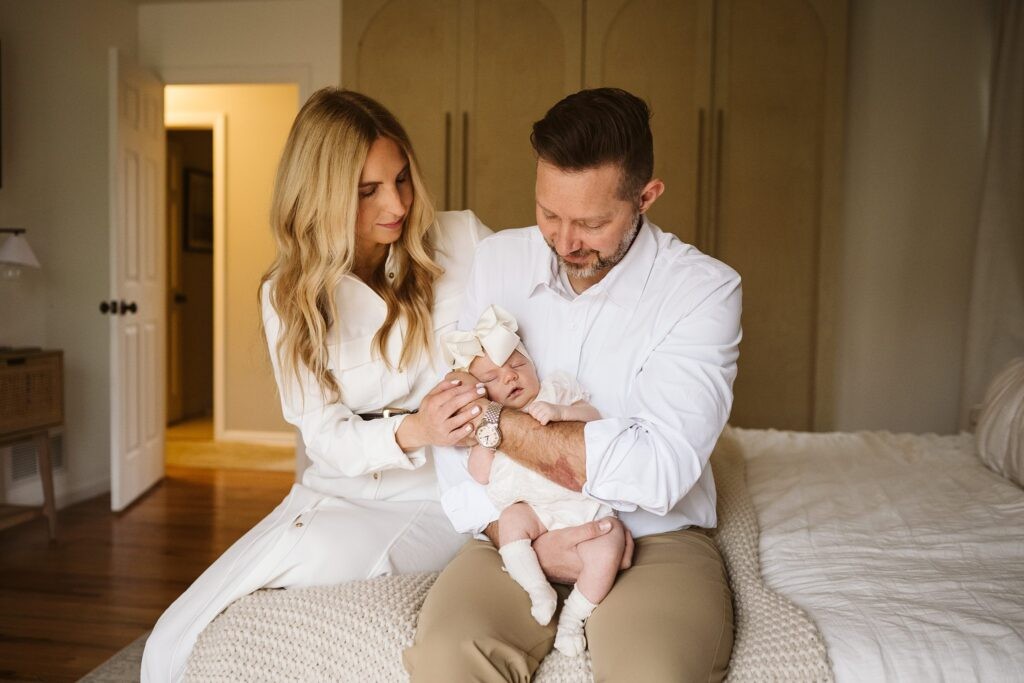 parents holding newborn baby on bed