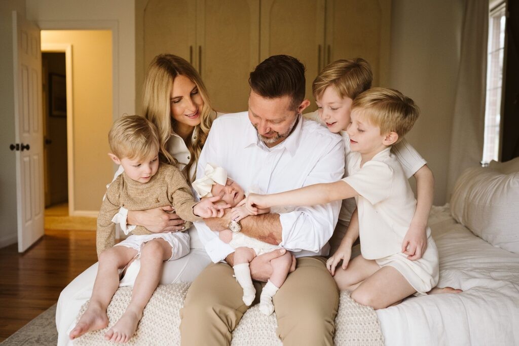 lifestyle portrait of family sitting on bed with newborn