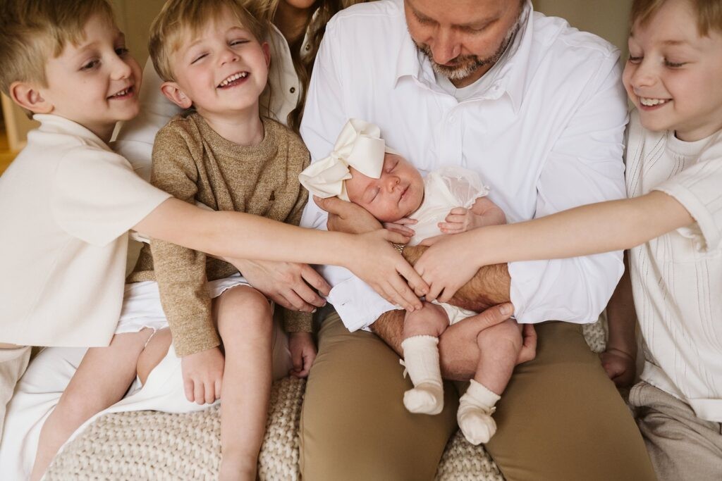 lifestyle portrait of family sitting on bed with newborn