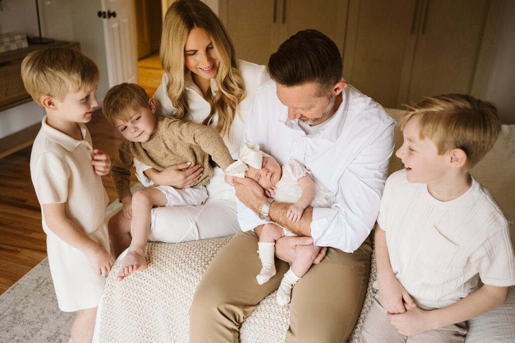 lifestyle portrait of family sitting on bed with newborn