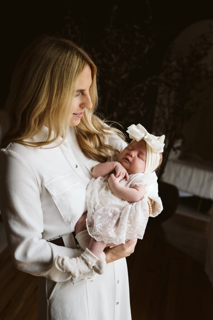 mom holding newborn in window light