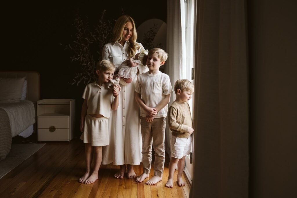 mom holding newborn with older siblings nearby