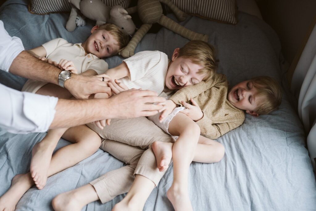 dad's hands tickling three boys