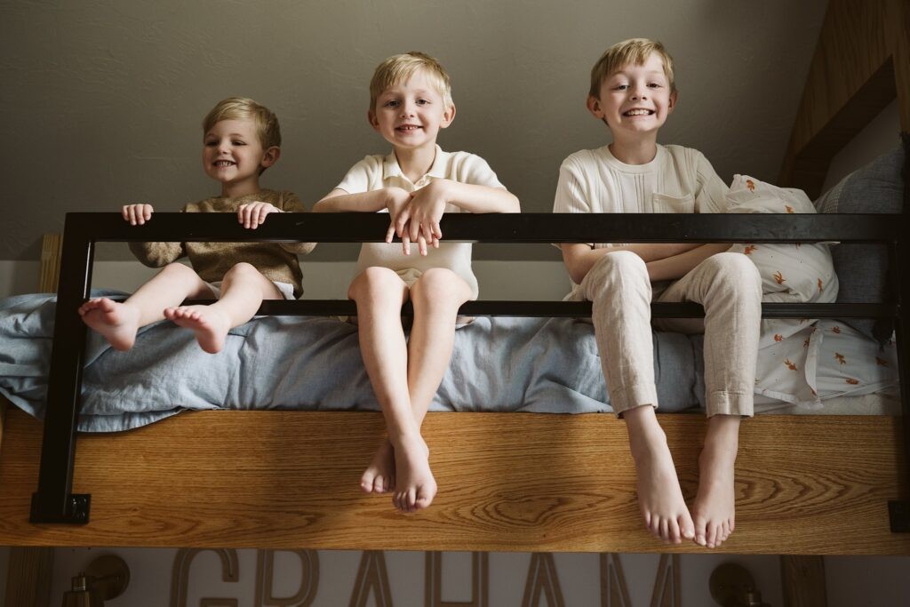 Three brothers sitting together on the top bunk of a bed
