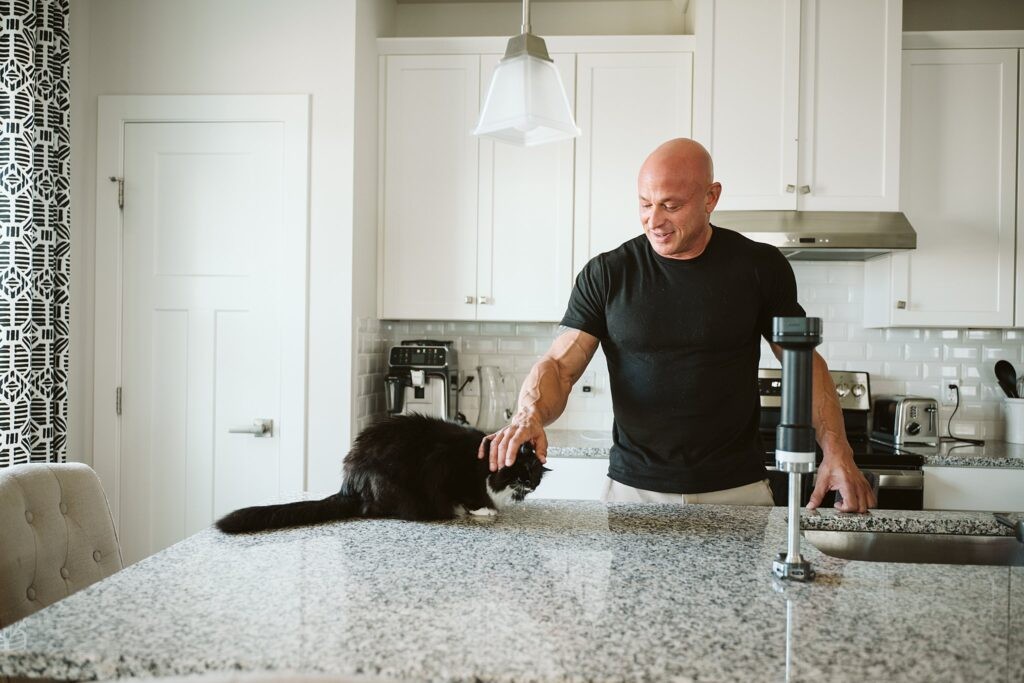 editorial portrait of man at kitchen counter with cat