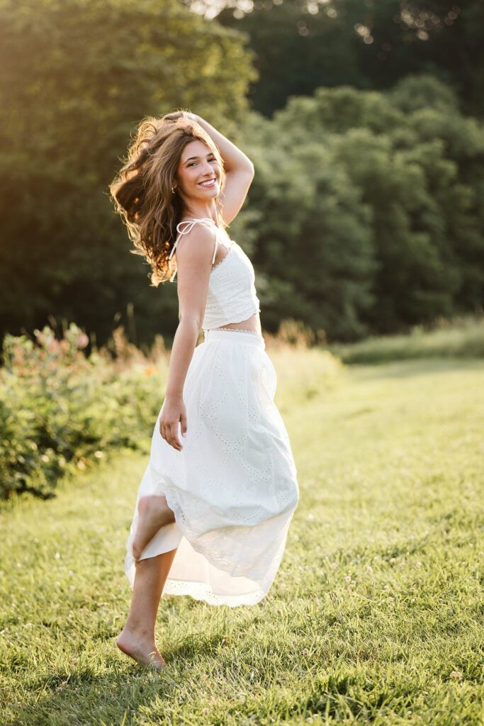 High school senior girl dancing in field during golden hour