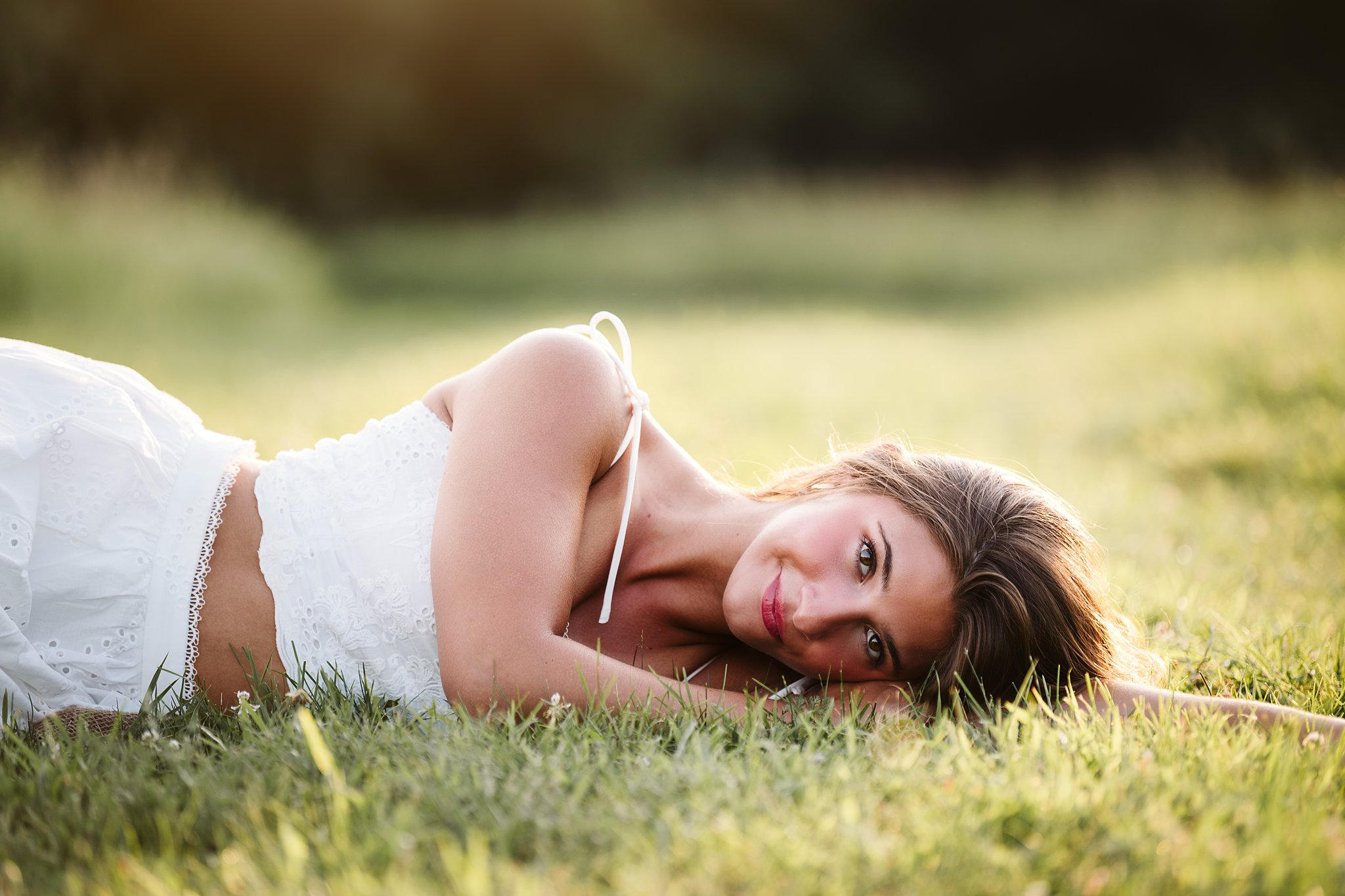 High school senior girl laying in field during golden hour