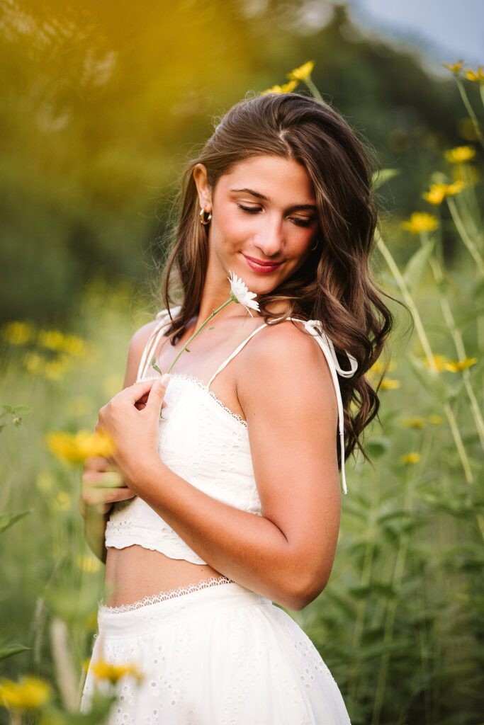 High school senior girl holding a flower in golden hour light