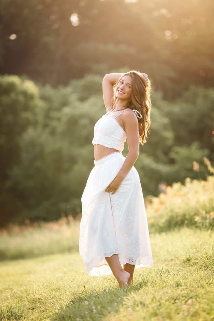 High school senior girl dancing in field during golden hour