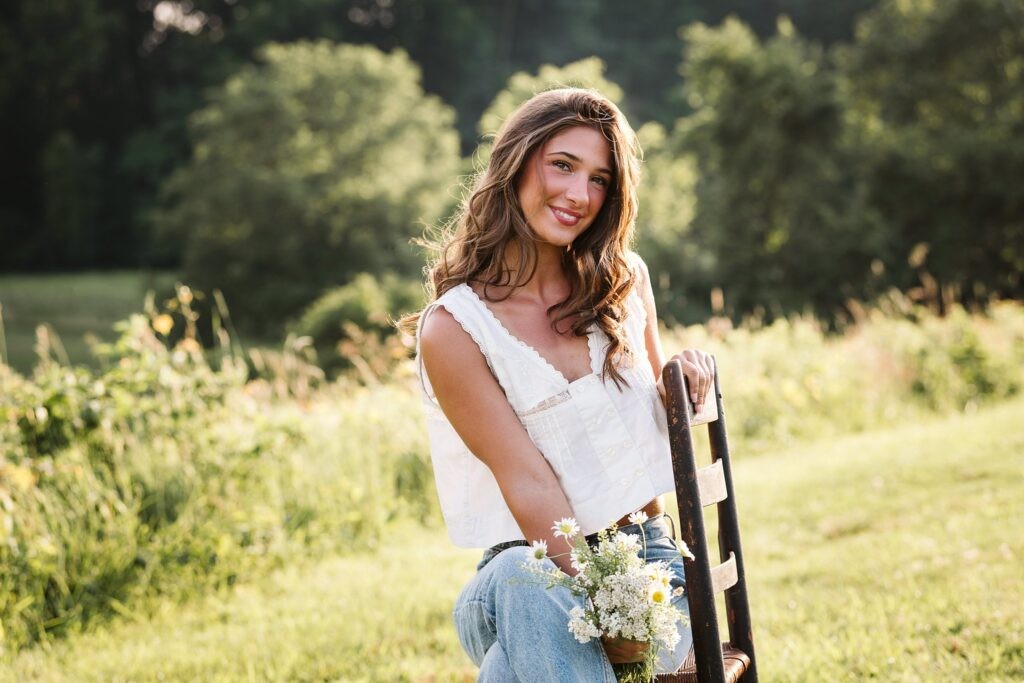 High school senior girl sitting in field during golden hour