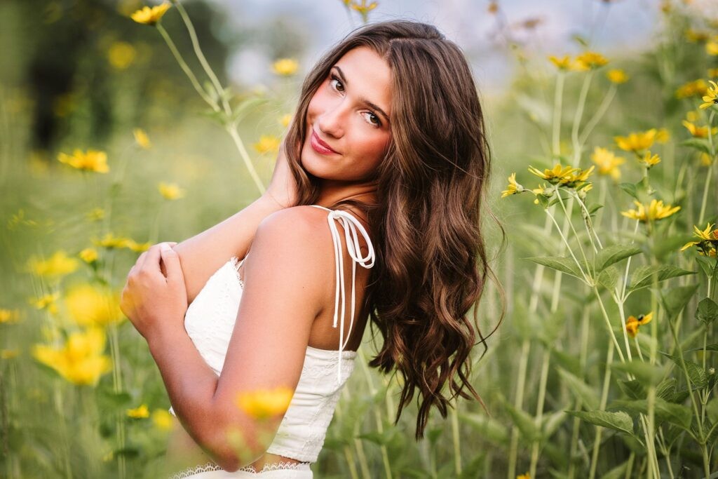 High school senior girl holding a flower in golden hour light
