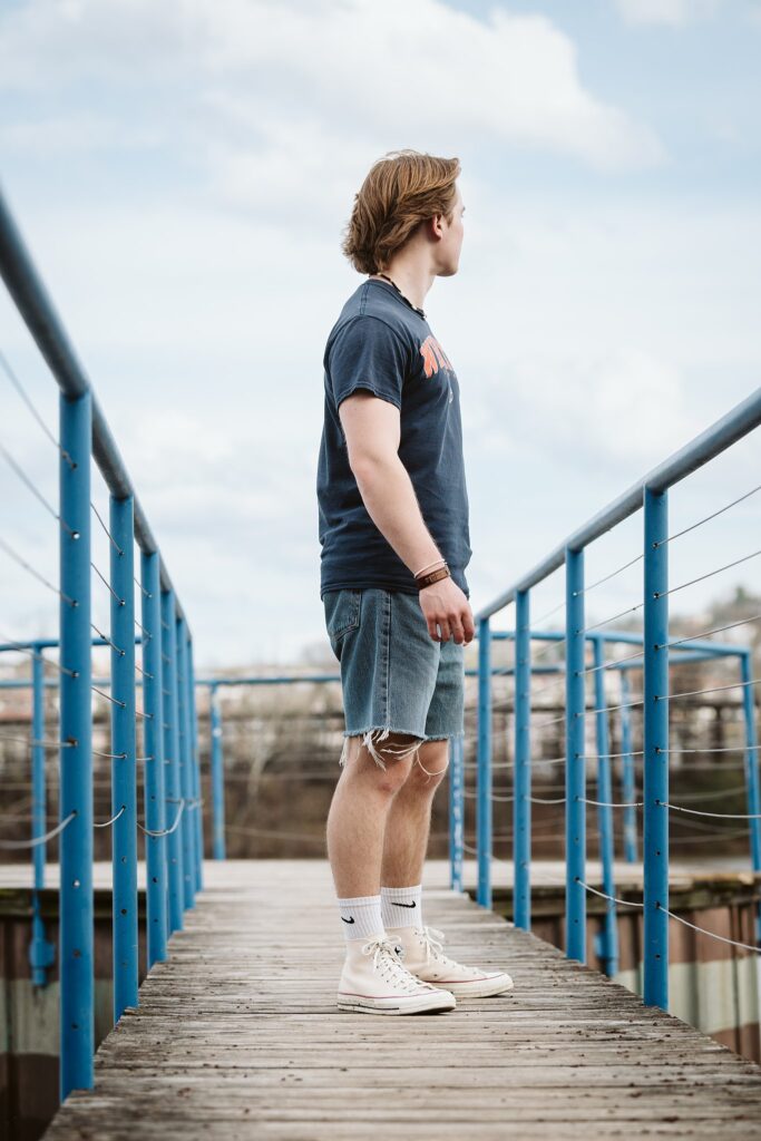 Artistic senior portraits for a guy at Washington’s Landing in Pittsburgh, featuring a relaxed style against the riverfront and boardwalk views.