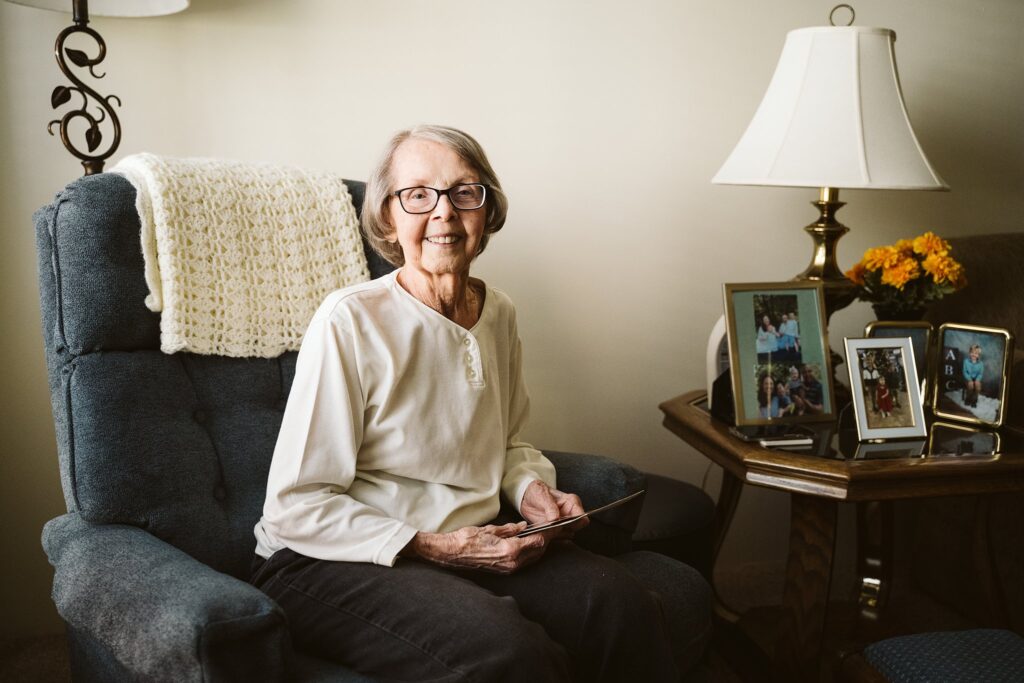 editorial photograph of senior woman at home with family photos