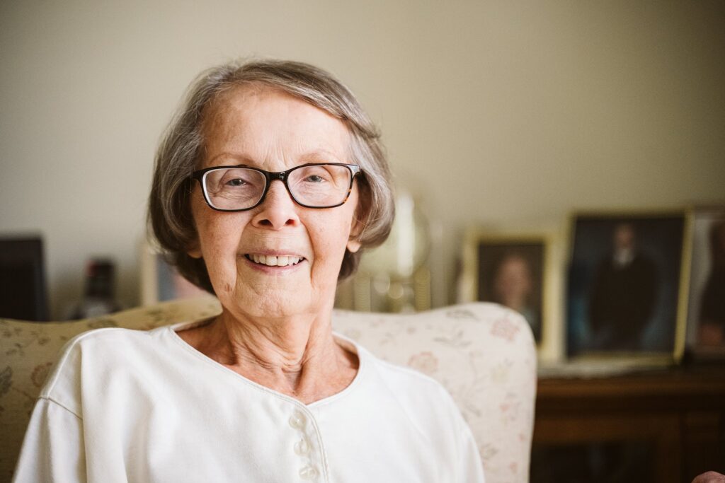 editorial photograph of senior woman at home with family photos