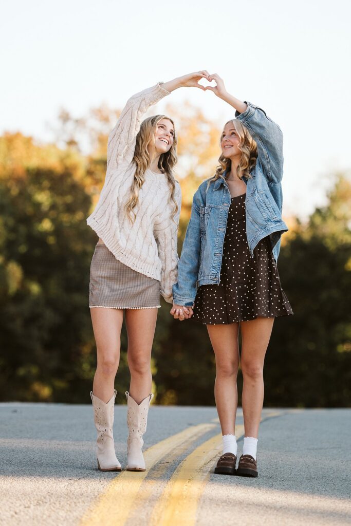 Two sisters making a heart with their hands in beautiful natural light during a Pittsburgh family photography session