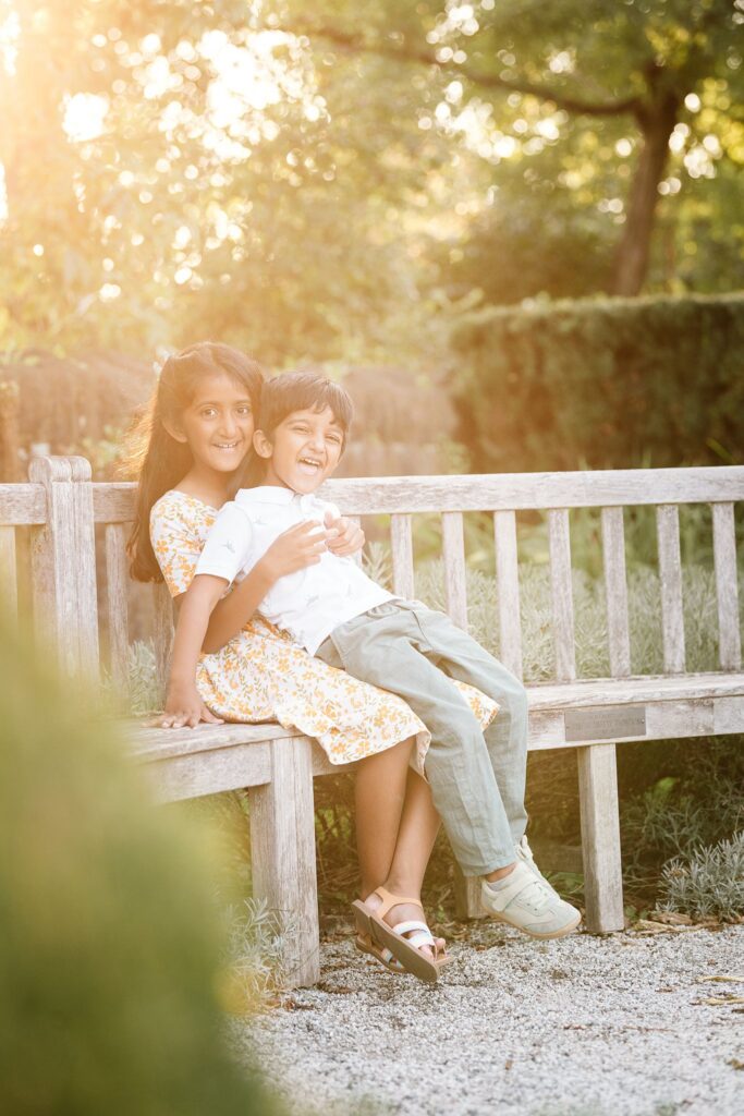 siblings hugging on a bench in a garden