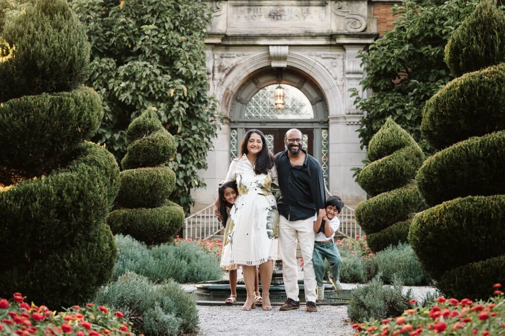 kids hiding behind parents during photoshoot in a garden